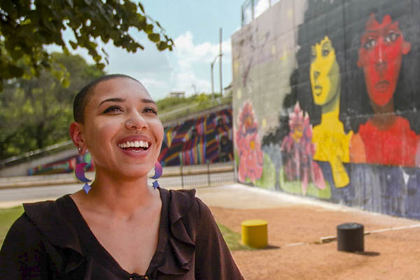 Artist Sadé Channell Lawson poses with her mural It's Okay Not to Be Okay on South Lamar in Austin