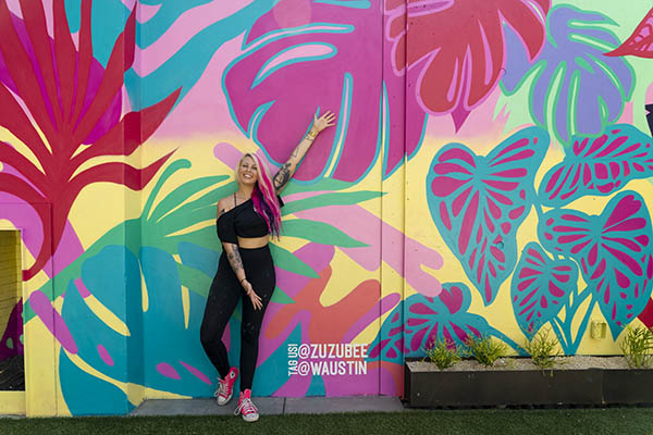 Artist Zuzu posing with her mural Paradise Found on the roof of the W Austin Hotel