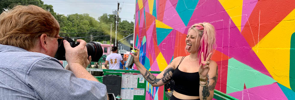 Artist Zuzu posing in front of a mural she created in Austin